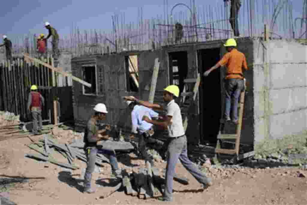 Palestinian men work on a construction site in the West Bank Jewish settlement of Kiryat Arba, near Hebron, 20 Oct 2010