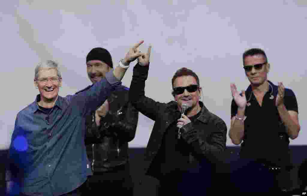 Apple CEO Tim Cook (left) smiles next to U2 members, The Edge, Bono, and Larry Mullen Jr. during an announcement of new products, in Cupertino, California, Sept. 9, 2014.