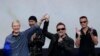 Apple CEO Tim Cook (left) smiles next to U2 members, The Edge, Bono, and Larry Mullen Jr. during an announcement of new products, in Cupertino, California, Sept. 9, 2014.