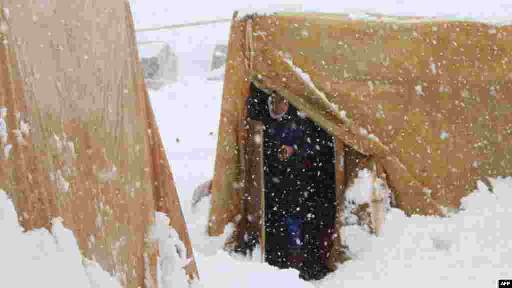 A Syrian refugee stands at the entrance of her tent during a snow storm at an unofficial camp on the road between Riyaq and Baalbek in Lebanon's eastern Bekaa Valley, near the border with Syria, Jan. 7, 2015. 