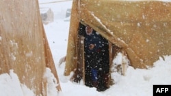 یک آواره سوری در برابر چادرش در یک اردوگاه آوارگان سوری در توفان برف ایستاده است. ۷ ژانویه ۲۰۱۵