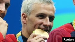 American swimmer Ryan Lochte bites into his gold medals after the men's 4x200m freestyle relay final in the Rio 2016 Summer Olympic Games in Rio de Janeiro, Aug. 9, 2016. (Jason Getz-USA TODAY Sports )