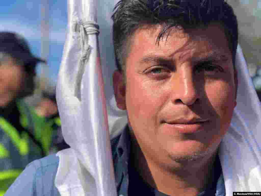 José Rodríguez, 30, from Siguatepeque, Comayagua, Honduras, carries a white flag the caravan brought during their march, which arrived at a pedestrian crossing in Tijuana, Mexico, Nov. 22, 2018. Celia Mendoza/VOA