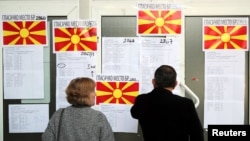 People look for their name on a list as they come to cast their ballot for the referendum in Macedonia on changing the country's name that would open the way for it to join NATO and the European Union in Skopje, Macedonia, Sept. 30, 2018. 