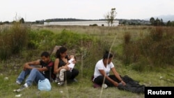 FILE - A group of Central American immigrants sit between vegetation for fear of organized crime bands in Huehuetoca, near Mexico City, June 1, 2015. An increasing number of Central Americans are sneaking across Mexico's border en route to the United States.