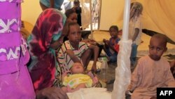 FILE - A family of refugees from the Central African Republic sit under a tent with their newborn baby at a camp in the eastern Cameroonian city of Garoua-Boulai.