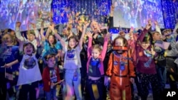 In this photo provided by NASA, a NASA scientist celebrates with school children at the exact moment that the New Horizons spacecraft made the closest approach of Kuiper Belt object Ultima Thule, Jan. 1, 2019, in Laurel, Md. 