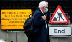 A man wearing a face mask walks past a coronavirus sign during the second nationwide lockdown in London, Nov. 10, 2020.