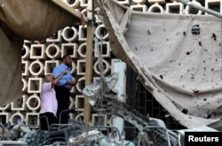 Egyptian investigators are seen in front of the damaged facade of the National Cancer Institute after an overnight fire from a blast, in Cairo, Egypt, Aug. 5, 2019.