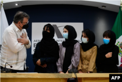 The Mexican Secretary of Foreign Affairs Marcelo Ebrard (L) welcomes four Afghan women, members of the Afghanistan Robotic team, during their arrival to Mexico after asking for refuge, at the Airport in Mexico City, on August 24, 2021.
