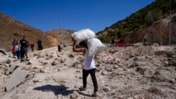 People carry belongings as they cross into Syria on foot, through a crater caused by Israeli airstrikes aiming to block Beirut-Damascus highway at the Masnaa crossing, in the eastern Bekaa Valley, Lebanon, Oct. 5, 2024.