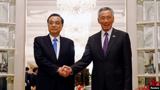 新加坡总理李显龙在新加坡总统府与中国总理李克强握手。（2018年11月12日）