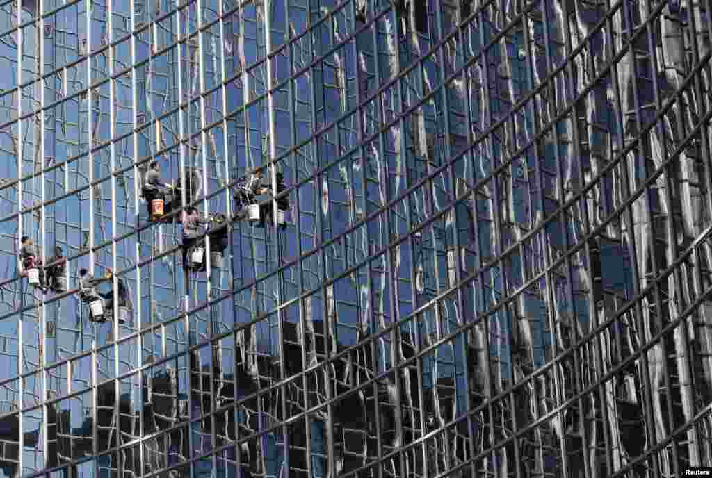 Workers clean a glass wall at a hotel in Beijing, China.