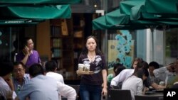 A woman orders cups of coffee at a Starbucks cafe in Beijing, China. (June 2011.)