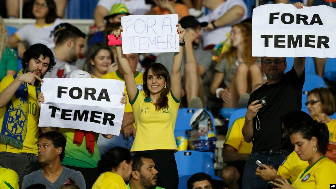 fans hold signs that read in Portuguese; "Temer Out" prior to a group E match of the women's Olympic football tournament between Brazil and Sweden at the Rio Olympic Stadium in Rio de Janeiro, Brazil, Aug. 6, 2016.