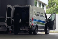 A body is loaded into a Miami-Dade County Medical Examiner's van outside Jackson Health Center, where coronavirus disease (COVID-19) patients are treated, in Miami, Florida, July 13, 2020.