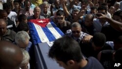 Friends and family of the late Cuban activist Oswaldo Paya carry his flag draped coffin during his burial at a cemetery in Havana, Cuba, July 24, 2012.