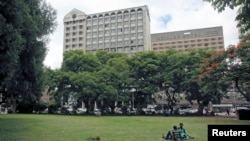 FILE: Zimbabweans rest at a park outside Meikles Hotel in central in Harare, February 24, 2015.