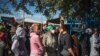 Pessoas em fila aguardam a distribuição de comida num parque de estacionamento em Orlando East Communal Hall, Soweto, Joanesburgo, 17 de abril, 2020. (Photo by MARCO LONGARI / AFP)