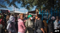 Pessoas em fila aguardam a distribuição de comida num parque de estacionamento em Orlando East Communal Hall, Soweto, Joanesburgo, 17 de abril, 2020. (Photo by MARCO LONGARI / AFP)