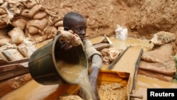 FILE: A boy washes gold dust in a plastic filter at a local goldmine in Bagega village in northeastern state of Zamfara 8.14.2013