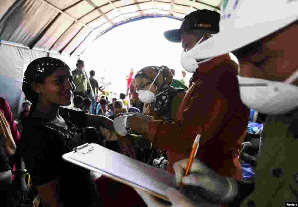 Petugas imigrasi Indonesia mencatatkan seorang perempuan Rohingya, yang tiba di Aceh dengan kapal, di dalam tempat penampungan sementara di Kuala Langsa, Aceh (16/5). (Reuters/Beawiharta)