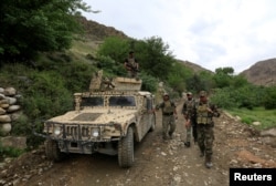 FILE - Afghan Special Forces patrol at the site of a MOAB, or ''mother of all bombs'', which struck the Achin district of the eastern province of Nangarhar, Afghanistan April 23, 2017.