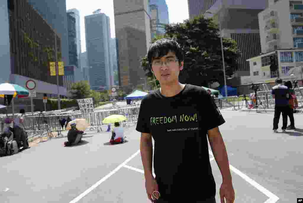 Pro-democracy student leader Alex Chow walks by Hong Kong's Chief Executive Leung Chun-ying's office where a few student protesters are sitting and staging their protest in Hong Kong, Oct. 6, 2014.