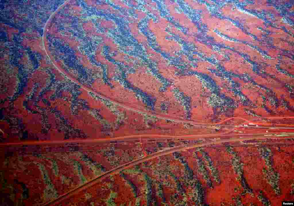 Roads go off in various directions next to sand dunes covered in vegetation in the Pilbara region of Western Australia.