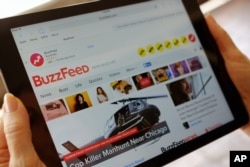 FILE - The BuzzFeed website is displayed on an iPad held by an Associated Press staffer in Los Angeles, Sept. 1, 2015.