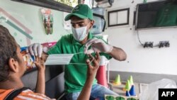 Un travailleur social montre à un enfant sans-abri comment utiliser un masque, dans une unité mobile gérée par les autorités égyptiennes dans le cadre du programme "Enfants sans domicile", au Caire, le 22 juin 2020. (Khaled Desouki/AFP)