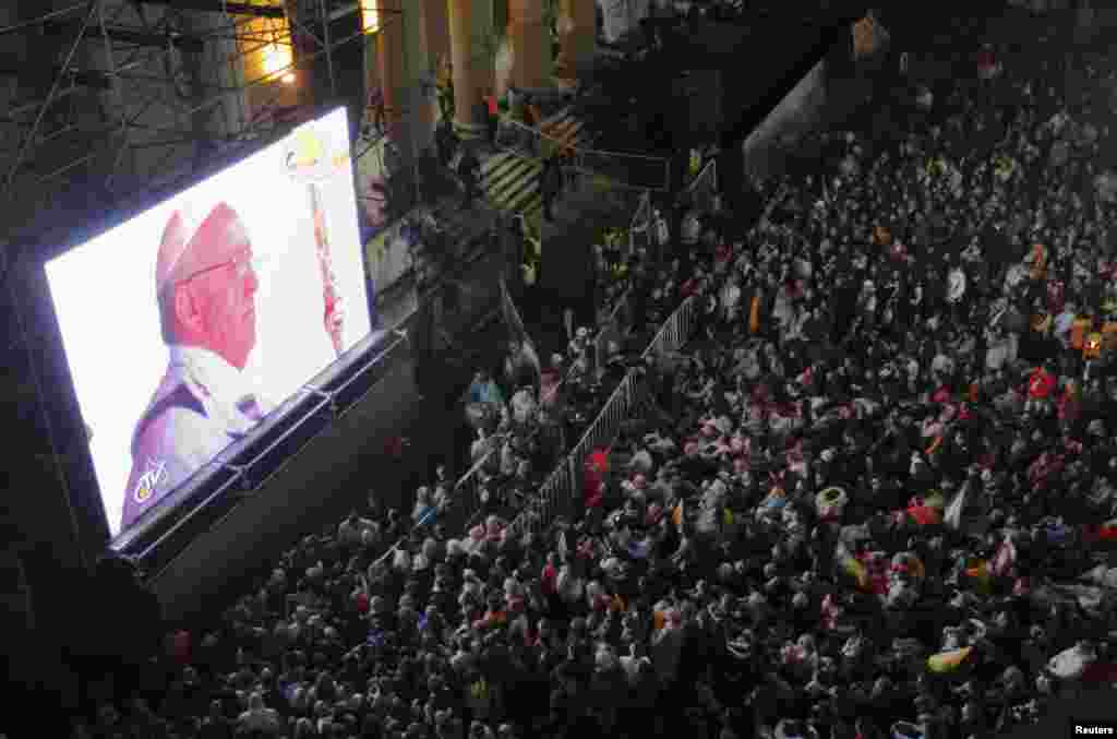 Faithful watch the inaugural mass of Pope Francis on a giant screen next to the Metropolitan Cathedral in Buenos Aires, Mar. 19, 2013.