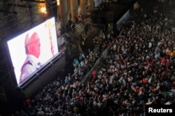 FILE - Faithful watch the inaugural mass of Pope Francis on a giant screen next to the Metropolitan Cathedral in Buenos Aires, March 19, 2013.
