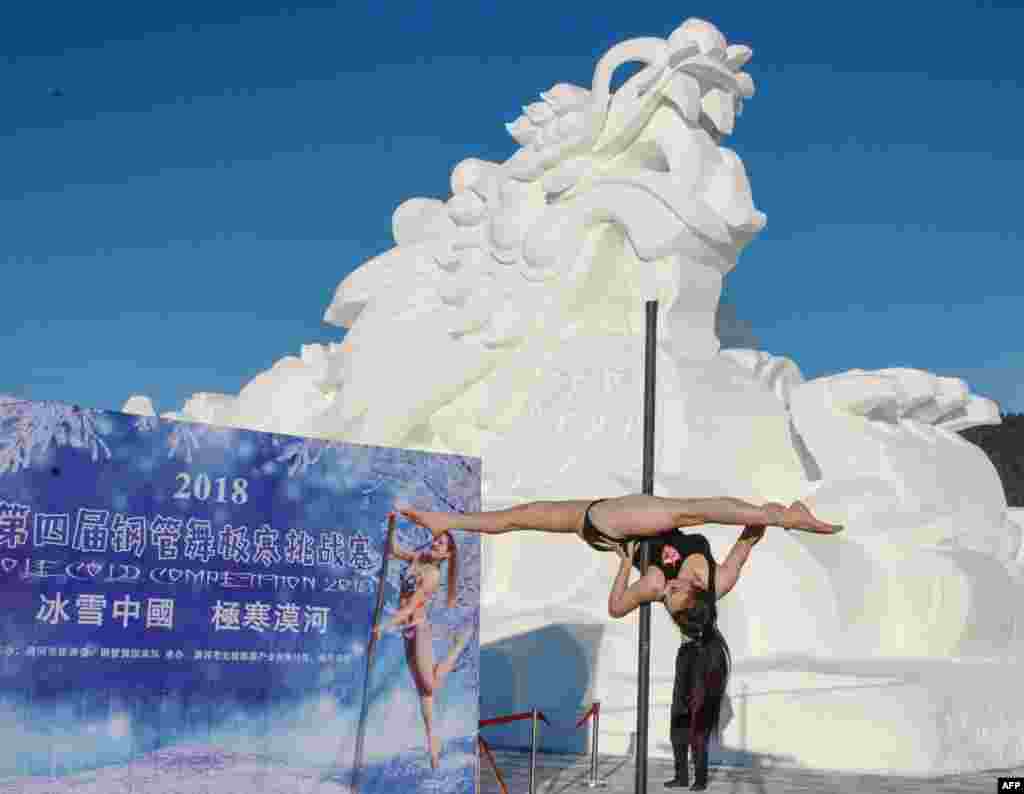 A dancer competes in front of a dragon snow sculpture during a pole dancing competition in a temperature of minus 23 degrees Celsius in Mohe in China's northeastern Heilongjiang province.