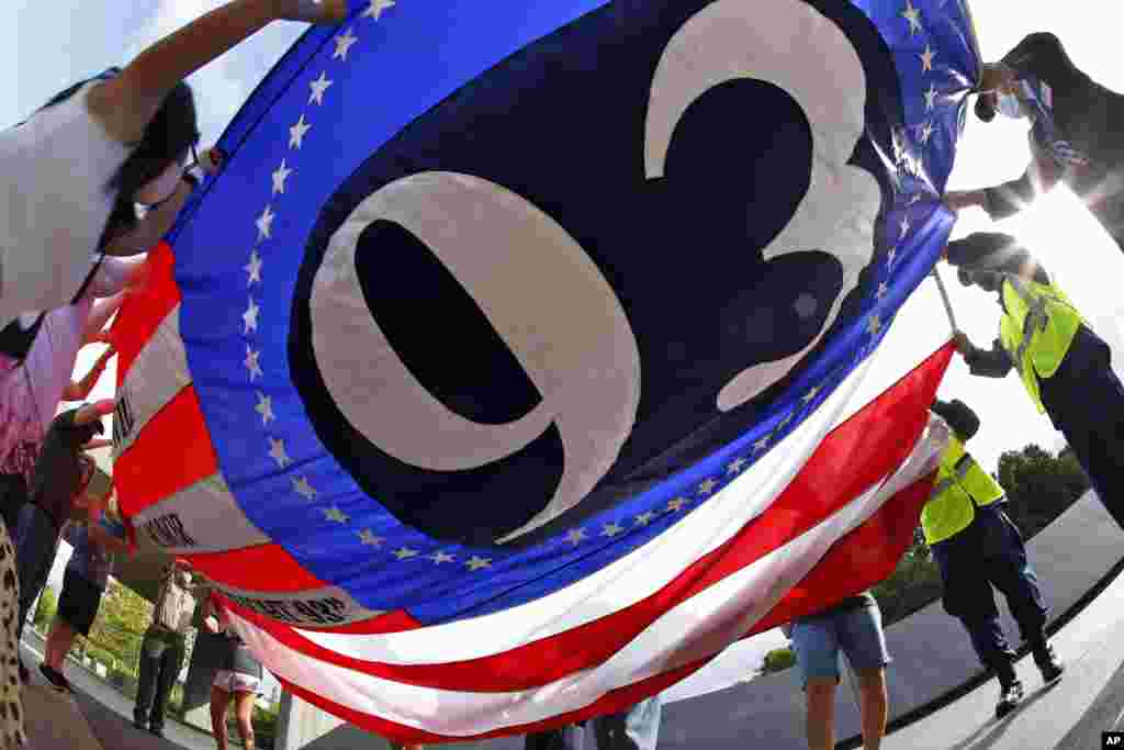 Visitors to the Flight 93 National Memorial in Shanksville, Pa., unfold a flag commemorating Flight 93 for a memorial service on Thursday, Sept. 10, 2020, as the nation prepares to mark the 19th anniversary of the Sept. 11, 2001, attacks. (AP Photo/Gene J. Puskar)