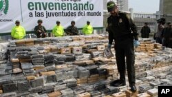 FILE - Colombia National Police Chief Rodolfo Palomino walks on seized packages of cocaine displayed for a press briefing in Cartagena, April 10, 2014. U.S. and Colombian authorities have issued warrants for 29 suspects accused of smuggling cocaine.