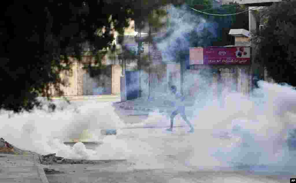 A Palestinian takes cover from tear gas fired by the Israeli troops during clashes with Palestinians in the West Bank city of Jenin, July 2, 2014.