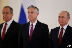 Russian President Vladimir Putin, right, smiles receiving credentials from the U.S. Ambassador, Jon Huntsman, center, during a ceremony in the Kremlin in Moscow, Russia, on Tuesday, Oct. 3, 2017.