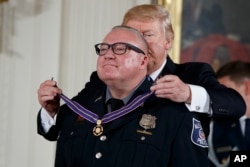 President Donald Trump presents the Medal of Valor to Kevin Jobe of the Alexandria, Virginia Police Department during a ceremony in the East Room of the White House in Washington, July 27, 2017.