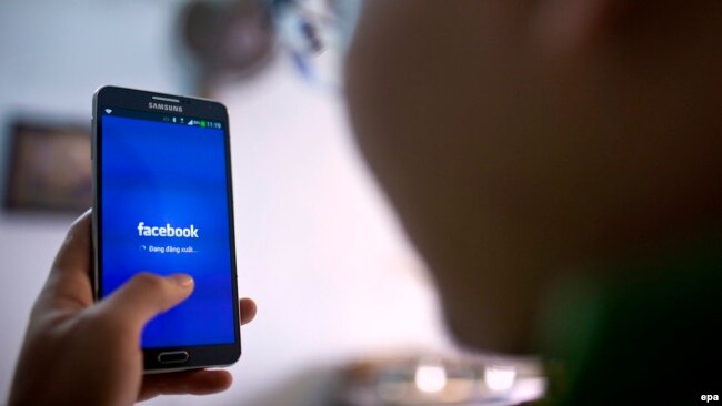 FILE - A man uses the social networking site Facebook on his phone in a cafe in Hanoi, Vietnam, 28 November 2013. (EPA/LUONG THAI LINH)