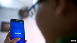 In this file photo, a man uses the social networking site Facebook on his phone in a cafe in Hanoi, Vietnam, on November 28, 2013. EPA/LUONG THAI LINH