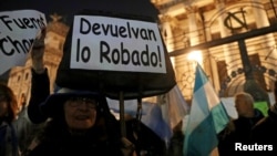 A woman holds up a sign that reads “give back what was stolen” during a demonstration against corruption and to demand the Senate strip former Argentine president and senator Cristina Fernandez de Kirchner of immunity, in Buenos Aires, Argentina, Aug. 21, 2018.