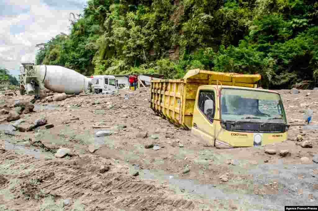 Trucks belonging to sand miners sit buried by volcanic ash after heavy rains shifted ash from the slopes of Indonesia&#39;s most active volcano, Merapi, in Magelang.