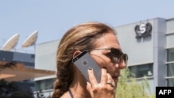 FILE - An Israeli woman uses her iPhone in front of the building housing the Israeli NSO group, Aug. 28, 2016, in Herzliya, near Tel Aviv. 