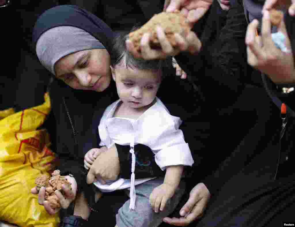 Asmaa Aljuned, holding her infant son, throws dirt into the grave of her husband, Malaysia Airlines MH17 First Officer Ahmad Hakimi Hanapi, in Putrajaya, Aug. 22, 2014.