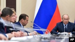 Russian President Vladimir Putin, right, presides over a cabinet meeting at the Novo-Ogaryovo residence outside Moscow, Russia, Sept. 27, 2017. Russian officials reported the destruction of the country's last remaining artillery projectiles filled with a toxic agent to Putin Wednesday.