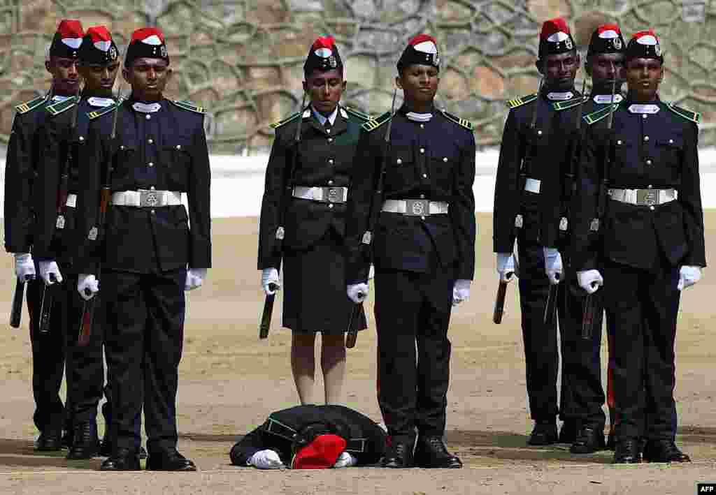 Sri Lankan officer cadets stand to attention for the national anthem as one of their colleagues faints during a passing out parade ceremony for 161 new army officers&#39; graduation in Diyatalawa.