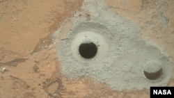 Xe thăm dò Curiosity của NASA dùng máy khoan nơi cuối cánh tay robot để khoan một hòn được gọi là "John Klein" trên Sao Hỏa.
