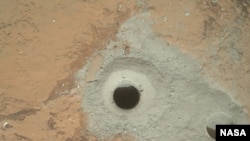 At the center of this image from NASA's Curiosity rover is the hole in a rock called "John Klein" where the rover conducted its first sample drilling on Mars.