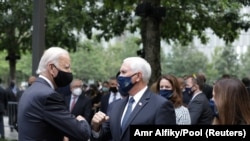 Le vice-président américain Mike Pence (à dr.) salue son prédécesseur, l'ancien vice-président Joe Biden, lors des commémorations des attentats du 11 septembre 2001 à New York, le 11 septembre 2020. (Amr Alfiky/Pool via REUTERS)